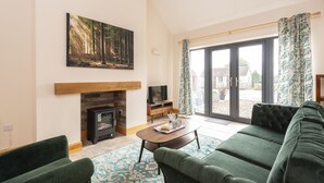 A living room with a fireplace, green sofa, and a painting of a forest. - A marketing that sleeps 2 guests  in 1 bedroom (Trowbridge)