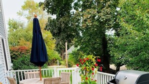 A wooden deck with a grill, outdoor seating, and a potted plant with flowers. - Jenness Beach Ocean Getaway - Book Now for Summer '26! (Rye)