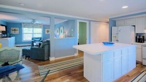A spacious living area with a large island, a kitchen with white cabinets, and a dining area with a blue couch. - Jenness Beach Ocean Getaway - Book Now for Summer '26! (Rye)