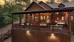 A rustic log cabin with a covered porch, wooden deck, and a cozy interior with seating and a fireplace. - Great family cabin! Huge deck! Creek! Mini cabin! Lots of amenities! (Hochatown)