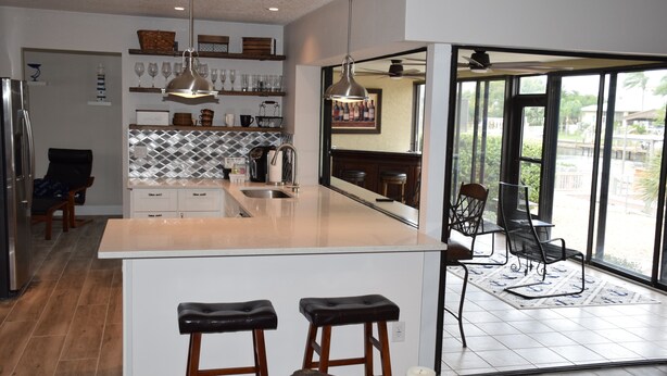 Una cocina moderna con una isla central, taburetes de bar y un comedor con vistas.