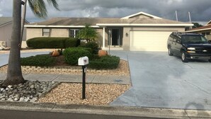 Una casa con garaje, entrada para vehículos, buzón y una palmera.