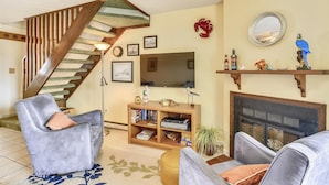 A living room with a staircase, a fireplace, a television, and a bookshelf. - Canal - Waterfront, WIFI, Walking Distance to Boardwalk / Beach Discount 6-27-26 (Ocean City)