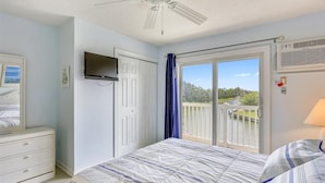A bedroom with a bed, a dresser, a TV, a ceiling fan, a window with a view of a boat, and a balcony with a railing. - Canal - Waterfront, WIFI, Walking Distance to Boardwalk / Beach Discount 6-27-26 (Ocean City)