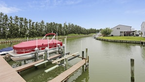 A dock with a red boat, a wooden pier, and a building in the background. - Canal - Waterfront, WIFI, Walking Distance to Boardwalk / Beach Discount 6-27-26 (Ocean City)