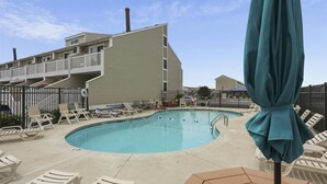 A swimming pool with lounge chairs and a covered area, surrounded by buildings. - Canal - Waterfront, WIFI, Walking Distance to Boardwalk / Beach Discount 6-27-26 (Ocean City)
