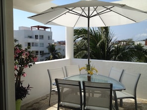 Relax on the balcony with a glass table and comfortable seating, taking in the views of the surrounding neighborhood.