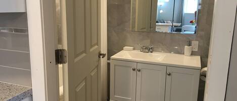 A bathroom with a white vanity, a mirror, and a sink.