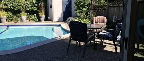 Un jardin avec une piscine, des meubles de patio et un espace salon abrité.