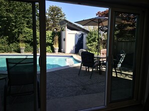 Un cortile con piscina, mobili da patio e un piccolo capanno.
