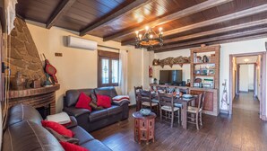 A cozy living room with a fireplace, a dining area, and a kitchen. - La Casita de Ronda by Ruralidays (Málaga)