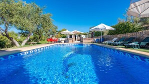 A swimming pool with clear blue water, surrounded by lounge chairs and umbrellas, and trees in the background. - La Casita de Ronda by Ruralidays (Málaga)