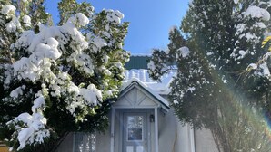 Uma casa pequena com porta branca e um pequeno alpendre.
