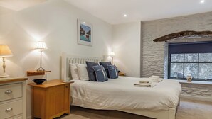 A bedroom with a bed, bedside lamps, a nightstand, a dresser, and a window with a view.