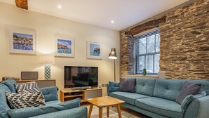A living room with a large flat-screen TV, two sofas, a coffee table, and a stone accent wall.