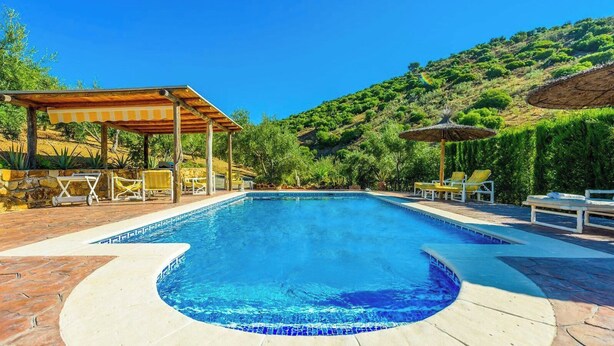 Ein Pool mit einer Holzpergola, Liegestühlen und Bergblick.