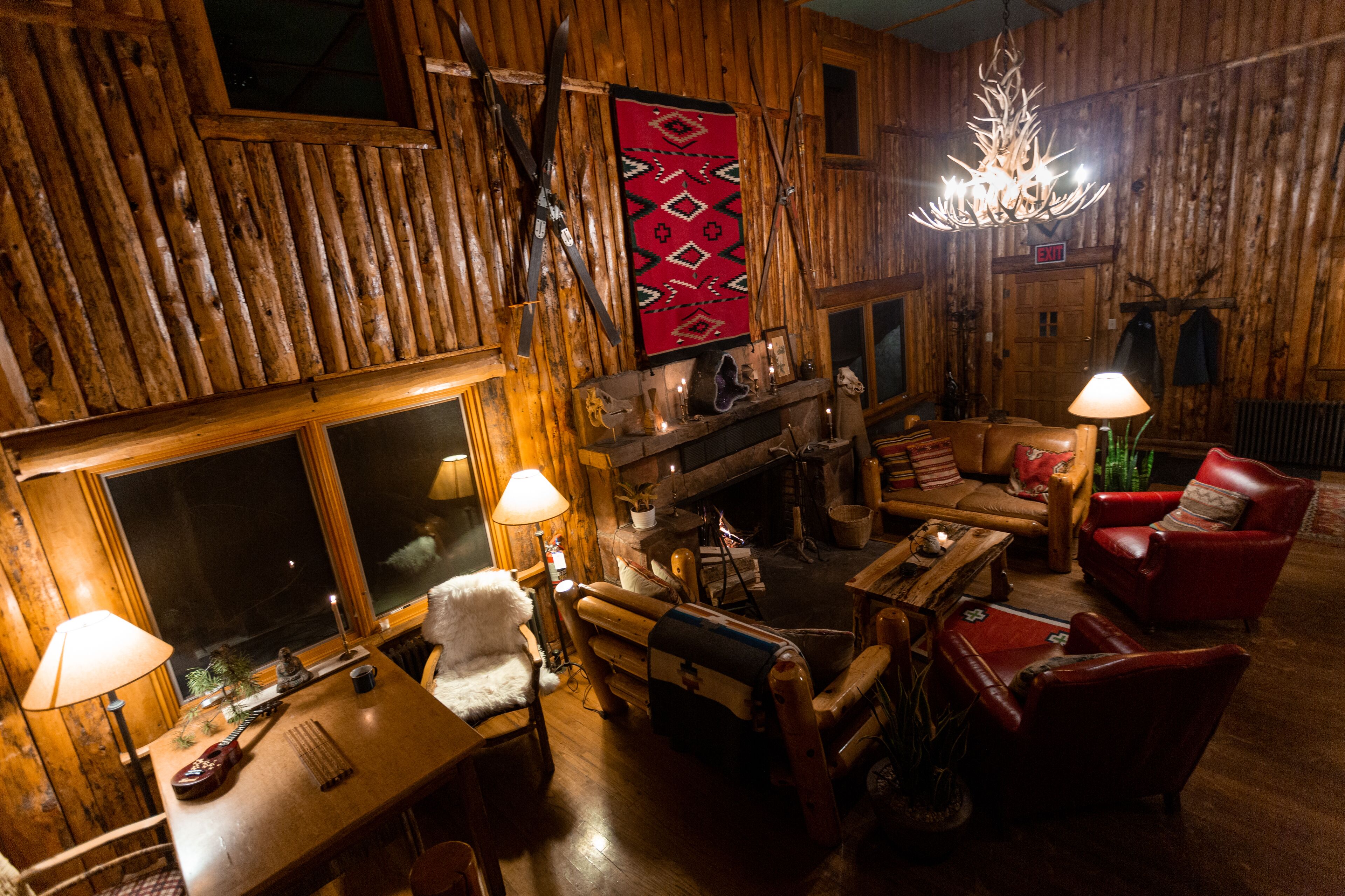 Un interior de cabaña de troncos acogedor, con chimenea, muebles de madera y una araña.