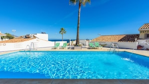 Una piscina con agua cristalina, rodeada de sillas de descanso y una palmera.