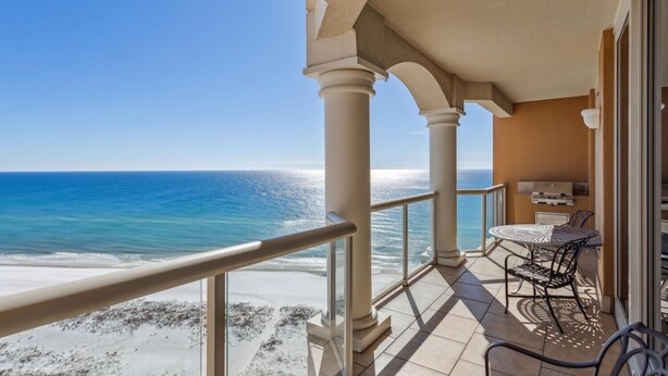 A balcony with a view of the ocean, a table, chairs, and a grill. - 2B Gulf Front Tower 3 20th Floor - Stunning Views! (Pensacola Beach)