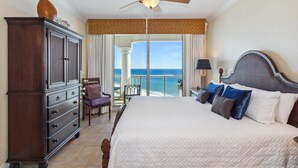 A hotel room with a large bed, a wardrobe, a chair, a nightstand, and a view of the ocean. - 2B Gulf Front Tower 3 20th Floor - Stunning Views! (Pensacola Beach)