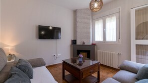 A living room with a flat-screen TV mounted on the wall, a fireplace, a sofa, and a coffee table. - Camino de la Huerta Montejaque by Ruralidays (Málaga)