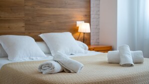 A neatly made bed with rolled towels, a lamp, and a wooden headboard in a hotel room. - Camino de la Huerta Montejaque by Ruralidays (Málaga)