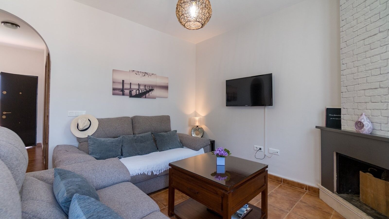 A living room with a sofa, a coffee table, a flat-screen TV, a fireplace, and a wall-mounted artwork.