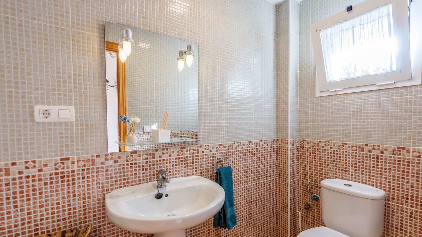 Une salle de bain avec un lavabo, un miroir et des toilettes.