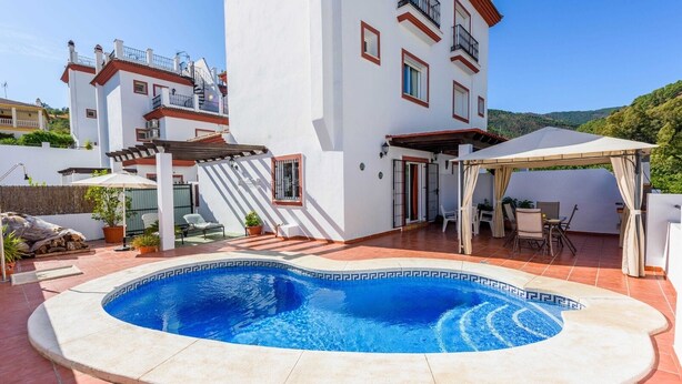 A swimming pool with a geometric tile design, surrounded by a covered patio area with outdoor furniture. - Casa Riu Tolox by Ruralidays (Málaga)