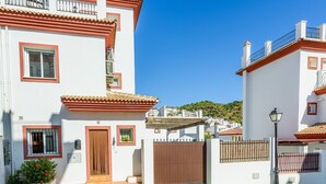 A white building with red accents, a wooden door, and a small window with a metal grill. - Casa Riu Tolox by Ruralidays (Málaga)