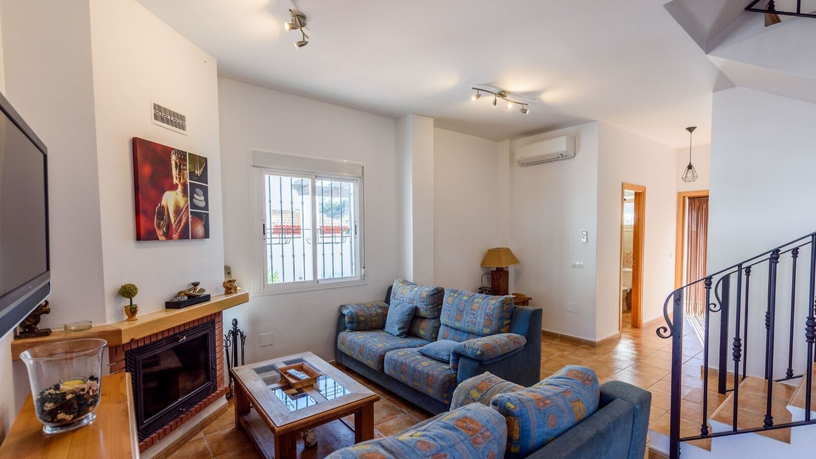 A living room with a fireplace, sofa, and television.