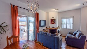 A living room with a sofa, a television, and a fireplace. - Casa Riu Tolox by Ruralidays (Málaga)