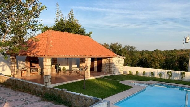 Una casa amb piscina, patis i zona d'estar exterior coberta.