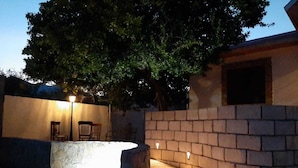 Un mur de pedra amb un llum, una pedraera i un arbre al fons.
