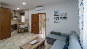 Een moderne woonkamer met een bank, een houten salontafel en een eethoek met tafel en stoelen.