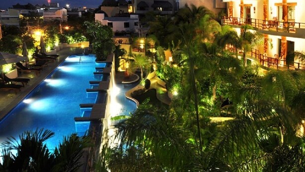 A resort with a swimming pool, palm trees, and buildings with thatched roofs. - Ocean View 3 story Penthouse with private rooftop, jacuzzi, and balconies (Playa del Carmen)