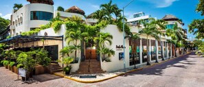 Un hotel con fachada curva, área de asientos al aire libre y palmeras.