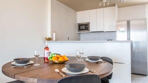 A modern kitchen with white cabinets, a stainless steel refrigerator, and a microwave. - Capistrano Garden Nerja by Ruralidays (Málaga)