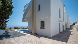 A modern building with a pool, a clear view of the sea, and a paved walkway. - Capistrano Garden Nerja by Ruralidays (Málaga)