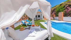 A poolside area with a canopy, lounge chairs, and a table with drinks. - Villa Manolo Torrox by Ruralidays (Málaga)