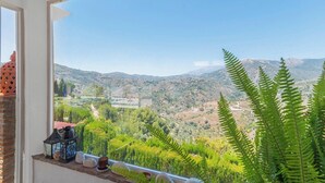 A balcony with a view of a mountainous landscape, a potted plant, and a lantern. - Villa Manolo Torrox by Ruralidays (Málaga)