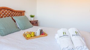 A neatly made bed with a tray of breakfast items, two rolled towels, and a small potted plant on a bedside table. - Villa Manolo Torrox by Ruralidays (Málaga)