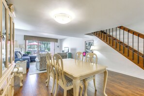 Un coin repas avec une table et des chaises, un escalier et un salon avec un canapé et une lampe.
