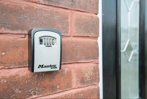 A Master Locks electronic keypad mounted on a brick wall.