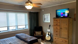 A bedroom with a bed, a ceiling fan, a television, a guitar, and a dresser. - Mountain Song - Villa with a View  (Beech Mountain)