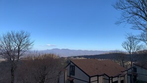 A house with a sloped roof and a view of mountains in the background. - Mountain Song - Villa with a View  (Beech Mountain)
