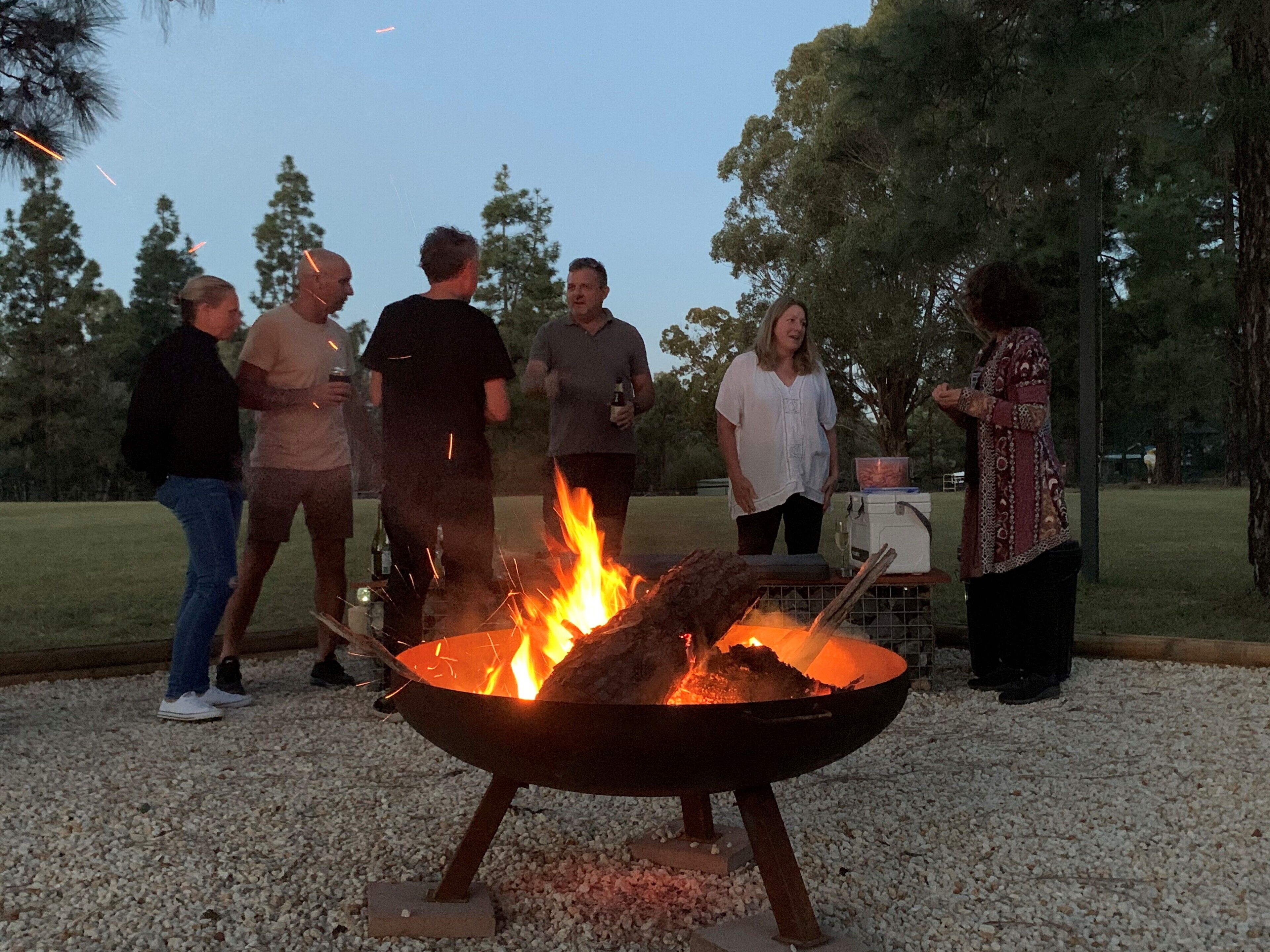 A group of people around a campfire in an outdoor setting.