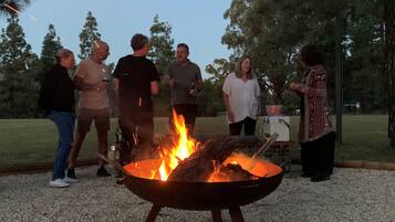 A group of people around a campfire in an outdoor setting.