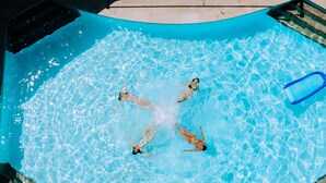 Una piscina con agua cristalina azul, un trampolín y una escalera.