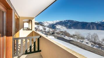 Un balcon avec vue sur des montagnes enneigées et une route.